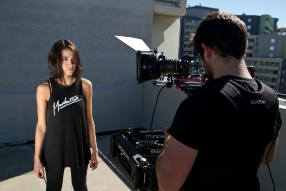 A person filming a woman on a rooftop in an urban setting.